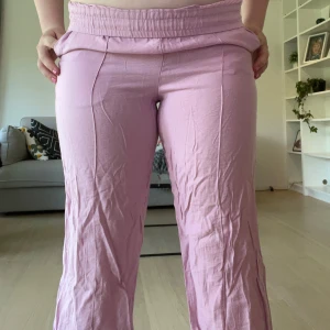 Ljusrosa byxor - Säljer ett par ljusrosa byxor från H&M med bred resår i midjan och raka, lite vidare ben. Obs jag har vikt ner kanten. Byxorna är knappt använda. Skriv vid frågor❤️❤️