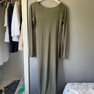 Grön långklänning från Boohoo - Snygg olivgrön långklänning från Boohoo med lång ärm och djup, öppen rygg. Klänningen är figurnära och har en enkel, stilren design utan mönster eller detaljer. Använt ett par fåtal gånger och är i storlekar 38 men ganska stor i storleken💓