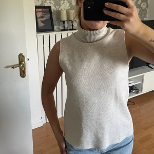 Beige ärmlös polotopp - Säljer en stilren beige polotopp utan ärmar. Toppen har en hög, ribbad polokrage och är gjord i ett mjukt stickat material. Perfekt att matcha med jeans eller kjol, från Zara ❣️