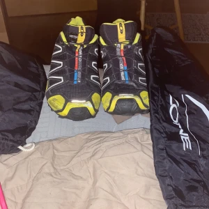 Salomon Speedcross 3 sneakers svart/gul - Salomon Speedcross 3 sneakers i svart och gul med vita detaljer och snabbsnörning. Skorna har en sportig design med robust sula och meshmaterial för bra ventilation. Perfekta för dig som gillar att sticka ut med färg och vill ha grymt grepp på löprundan.