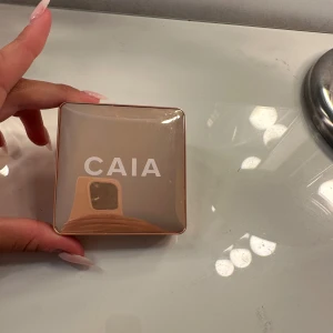 CAIA Highlighter Saint Tropez - Superfin highlighter från CAIA i nyansen Saint Tropez. Kommer i en lyxig, fyrkantig guldig dosa med spegel. Highlightern har en skimrande champagnefärg och en pressad cirkelmönstrad yta. Perfekt för att ge glow till kindben, näsa och brynben.