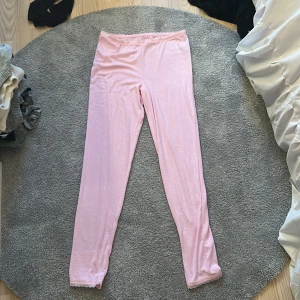 Ljusrosa leggings med spetskant - Säljer ett par ljusrosa leggings i mjukt och stretchigt material. De har en smal passform och en söt liten spetskant längst ner vid bensluten. Perfekta att styla med en oversized hoodie eller t-shirt.