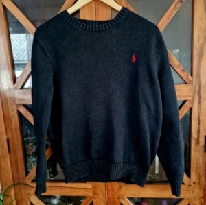 Svart stickad tröja från Ralph Lauren - Säljer en stilren svart stickad tröja från Ralph Lauren med det klassiska röda logotypbroderiet på bröstet. Tröjan har långa ärmar och ribbade muddar vid ärmslut och nederkant. Perfekt för kyligare dagar!  Skick 8/10. Pris kan diskuteras vid snabb affär. Hör av er om ni har frågor. 