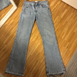 Blå jeans med bootcut - Säljer ett par ljusblåa bootcut jeans från Gina tricot då dem blivit försmå. Byxorna är snyggt slitna nertill och har en snygg passform. 