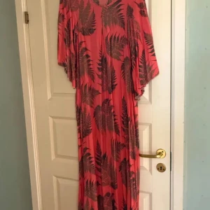 Rosa långklänning Hollister  - Säljer en rosa långklänning med ett snyggt bladmotiv i mörkare nyanser. Klänningen har en lös passform och kortärmade ärmar, perfekt för en avslappnad stil. Den är tillverkad i ett lätt och bekvämt material.