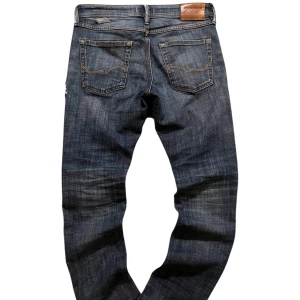 Blå jeans från Jack & Jones - Snygga blå jeans från Jack & Jones med klassisk femficksdesign och en läderpatch baktill. Perfekta för en avslappnad stil.