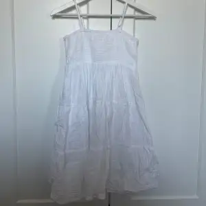 Säljer en  vit klänning från H&M med smala axelband och en luftig design. Klännigen är ribbad högst upp med luftig design och är i stolek 158. Perfekt för varma sommardagar. (Slutsåld)