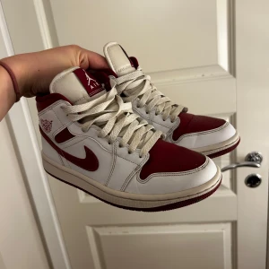 Nike Air Jordans i rött och vitt - Säljer ett par klassiska Nike Air Jordans i rött och vitt. Skorna har en snygg design med snörning och den ikoniska Air Jordan-loggan på sidan. Perfekta för dig som vill ha en stilren och sportig look.