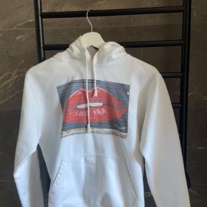 Vit hoodie med tryck av röda läppar - Snygg vit hoodie med ett ettt teyvk av läppar. Från märket the cool elephant!!