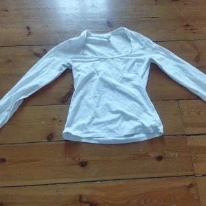 Vit långärmad topp från H&M - Säljer en stilren vit långärmad topp från H&M. Perfekt för lager-på-lager eller att bära som den är. Toppen har en enkel och klassisk design som passar till många olika stilar.