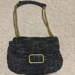 Marinblå väska med guldkedja!!!! - Snygg marinblå väska med ett elegant mönster och guldfärgad kedja. Väskan har  en praktisk dragkedja inuti. Perfekt för att ge din outfit en stilfull touch. Ny pris 600kr från mango!!!!