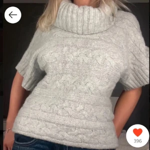 Grå stickad tröja med polokrage - Mysig grå stickad tröja med polokrage och korta ärmar. Perfekt för kyliga dagar med sitt kabelstickade mönster som ger en klassisk look. använd ett fåtal gånger