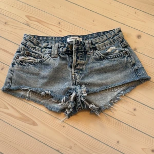 Ljusblå jeansshorts - Snygga jeansshorts  med fransiga kanter och slitna detaljer. Perfekta för en avslappnad sommarlook. De har en klassisk femficksdesign och är lågmidjade för en trendig stil.