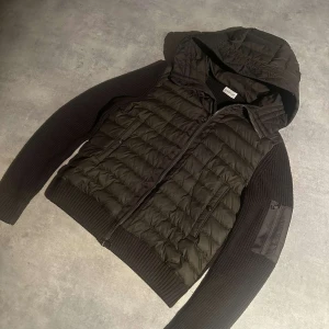 Grön cardigan från Moncler - Snygg grön cardigan från Moncler med quiltad design och huva. Den har långa ärmar och dragkedja framtill. Perfekt för kyligare dagar med sin stilrena look och praktiska fickor. Hör av vid minsta fundering💯