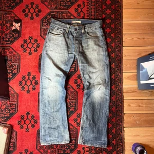 Levis 512 Bootcut Jeans - Säljer ett par klassiska Levis 512 bootcut jeans i en snygg ljusblå tvätt. De har en traditionell femficksdesign och en bekväm passform. Perfekta för en avslappnad stil.