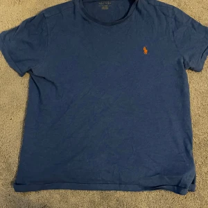 Blå t-shirt från Ralph Lauren - Säljer en klassisk blå t-shirt från Ralph Lauren med det ikoniska broderade logotypen i rött på bröstet. Passar bra till en sommar outfit! Tveka inte om frågor 👍
