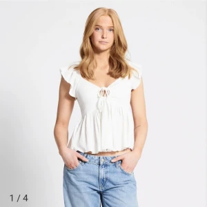 Vit blus med knytning - Säljer en söt vit blus med knytning framtill och volangdetaljer. Blusen har en luftig passform och korta ärmar, perfekt för varmare dagar. Den är tillverkad i ett lätt och bekvämt material. Orginalpris 150 kr. Lager 157 felicety