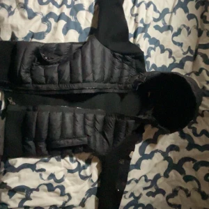 Svart dunväst från Moncler - Säljer en snygg svart dunväst från Moncler. Västen har en quiltad design med dragkedja framtill och praktiska fickor. Perfekt för lager-på-lager under kyliga dagar. Kan gå ner till 1400 vid snabba affär om ni har några frågor är det bara fråga