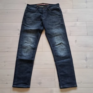 Mörkblå jeans från Jack & Jones - Snygga mörkblå jeans från Jack & Jones med klassisk femficksdesign och knappgylf. Perfekta för en avslappnad stil. De har en lätt tvättad look som ger en cool touch.