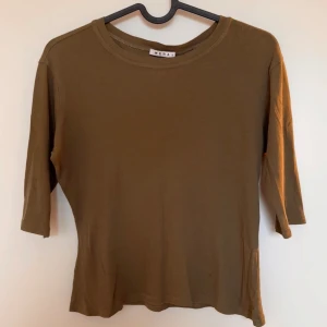 Olivgrön cropped t-shirt - Trendig olivgrön cropped t-shirt med trekvartsärmar. Mjuk och lite genomskinlig. Använd ett fåtal gånger.