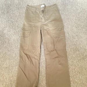 Gröna cargopants med snörning - Säljer ett par gröna cargopants med praktiska fickor på sidorna och snörning i midjan. 