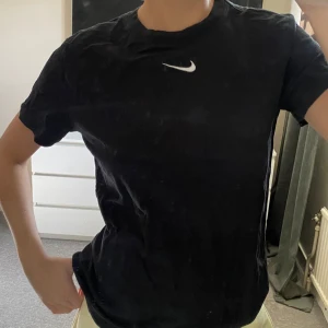 Svart t-shirt från Nike - Säljer en klassisk svart t-shirt från Nike med korta ärmar och en liten vit Nike-logga på bröstet. 