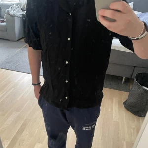 Snygg Svart linne skjorta från Zara - Säljer en stilren svart linne skjorta från Zara med korta ärmar och knappar framtill. Perfekt för en avslappnad men ändå snygg look på sommaren. 