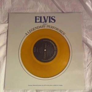 Elvis: A Legendary Performer Volume 2 - Säljer en samlarutgåva av 'Elvis: A Legendary Performer Volume 2' med en gul vinylskiva. Omslaget har en bild av skivan och innehåller låtar som 'Blue Suede Shoes' och 'Jailhouse Rock'. Perfekt för Elvis-fans och vinylsamlare! Bara prov lyssnar 1-2 gånger 
