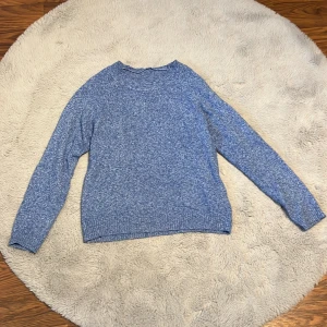 Blå stickad tröja från Vero Moda - Säljer en snygg blå stickad tröja från Vero Moda. Tröjan har en klassisk rund hals och långa ärmar, perfekt för kyligare dagar. Den är mjuk och bekväm, idealisk för både vardag och avslappnade tillfällen.