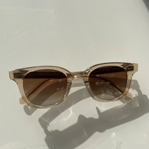 Chimi solglasögon - Ecru 02 - Snygga Chimi solglasögon i färgen ecru, modell 02. Glasögonen är i nyskick och är endast använda ett fåtal gånger. Köpeförpackningen kommer med och är i nyskick. Själva glasögonfodralet är lite skevt (se bild) men fungerar i övrigt bra. Påsen till glasögonen har förlorat ett snöre och har en liten fläck, men fungerar ändå väl! 