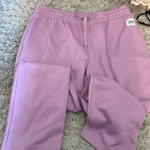 Lila mjukisbyxor från Lindy - Säljer ett par lila mjukisbyxor från Lindy. Byxorna har en elastisk midja med snörning för justerbar passform. Perfekta för en avslappnad stil.