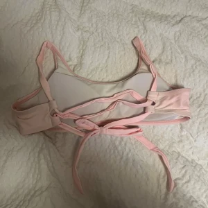 Rosa bikiniöverdel med knytband - Snygg rosa bikiniöverdel med knytband i sidan. Perfekt för en dag på stranden eller vid poolen. Den har en enkel och stilren design med smala axelband. Storlek M men som S