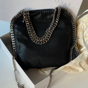 Stella McCartney liknade väska - Snygg svart axelväska som liknar den  från Stella McCartney. Den är använd men ändå i bra skick! Pris kan diskuteras. OBS‼️ en av kejdjorna har åkt ur sin ring men det är inget som syns och kan lätt fixas med en tång, har dock inga redskap hemma 
