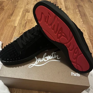 Christian Louboutin skor - Snygga svarta skor från Christian Louboutin med röda sulor och nitar på ovansidan. Skorna är köpta från Italien och helt oanvända.