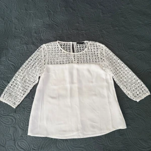 Vit blus från Stockh LM - Säljer en elegant vit blus från Stockh LM med vackra spetsdetaljer på ärmarna och övre delen. Blusen har trekvartsärmar och en rund halsringning. Tillverkad i polyester med bomullsdetaljer. Perfekt för en stilren look. Storlek 36 men enligt mig passar bättre 34(xs)