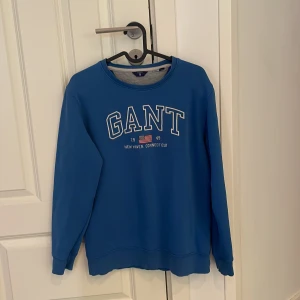 Blå sweatshirt från GANT - Säljer en snygg blå sweatshirt från GANT, tröjan har långa ärmar och en rund halsringning. Perfekt för en avslappnad stil.