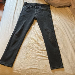 Mörk gråa  jeans från Jack & Jones - Säljer dessa snygga gråa jeans från Jack & Jones. Använda antal gånger. Passar på folk med längd 1.80 cm till 1.85 cm skulle jag säga. Storlek 32/34
