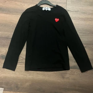 Svart långärmad tröja från Comme des Garçons - Säljer en svart långärmad tröja från CDG med det röda hjärtat på bröstet. . Tröjan är i storlek M men passar S och passar utmärkt till både vardag och speciella tillfällen.