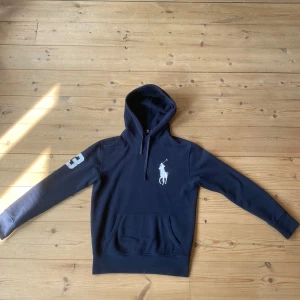 Mörkblå hoodie från Ralph Lauren - Säljer en snygg mörkblå hoodie från Ralph Lauren med en stor vit logga på bröstet och siffran 3 på ärmen. Tyvärr lite för liten för mig. Sjuk sällsynt 