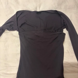 Mörk grå topp från Gina Tricot - Snygg mörk grå topp från Gina Tricot. Perfekt för en stilren look med långa ärmar och en tight passform. Passar utmärkt till både jeans och kjol.