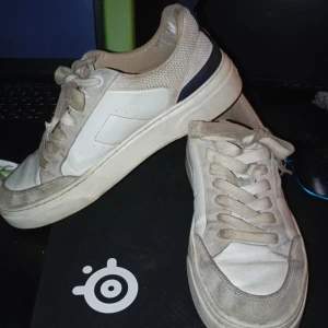 Vita sneakers från Björn Borg - Snygga vita sneakers från Björn Borg med marinblå detaljer och snörning. Skorna har en klassisk design med rund tå och är perfekta för en avslappnad stil. Märkesloggan syns tydligt på baksidan.har inte sko boxen och dem är lite slitna inuti pris kan diskuteras