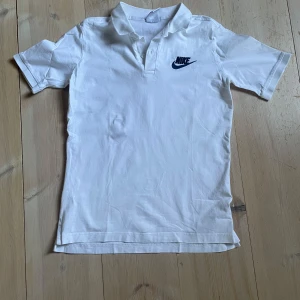 Pikétröja - Vit piketröja från Nike i bomulls material. Storlek 158-170 cm. Bra skick ca 6/10. Finns en pytteliten fläck på framsidan som knappt syns tyvärr
