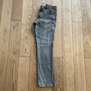Grå jeans från Wrangler - Snygga grå jeans från Wrangler med klassisk femficksdesign. Stl 32/34 Innerbenslängd ca: 84cm De har en rak passform och är perfekta för en avslappnad stil. Tillverkade i slitstarkt material som ger en bekväm känsla hela dagen.