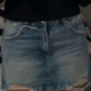 Blå jeanskjol från Pull&Bear - Snygg blå jeanskjol från Pull&Bear med slitna detaljer och rå kant. Kjolen har en klassisk femficksdesign och stängs med dragkedja och knapp. Perfekt för en avslappnad stil. Aldrig använd med prislappen kvar 😊💕