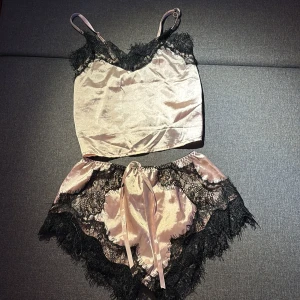 Pyamas set i silke - Rosa svart silke pyamas set, knappt använda . Med fint svart spets, shortsen är streckiga