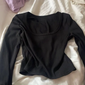 Svart ribbad topp - Säljer en stilren svart ribbad topp med långa ärmar och en rundad halsringning. Perfekt för en chic och enkel look. Det står ingen storlek men skulle tro att den är i xs/s