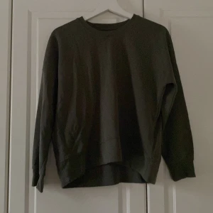 Mörkgrön tröja från NOOM - Säljer en stilren mörkgrön tröja från NOOM. Tröjan har en enkel design med långa ärmar och rund halsringning. Perfekt för en avslappnad look.