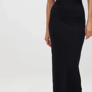 Svart långklänning - Elegant svart långklänning med en axelbandslös design. Perfekt för en stilren och sofistikerad look.