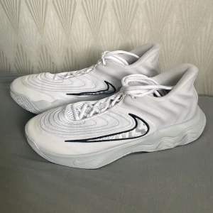 Nike Giannis Immortality 4 - Säljer ett par Nike Giannis Immortality 4 i vitt med svarta detaljer. Skorna har en modern design med snörning och en bekväm passform. Perfekta för basket eller vardagsbruk.