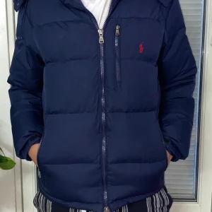 Mörkblå pufferjacka Polo Ralph Lauren - Snygg mörkblå pufferjacka från Polo Ralph Lauren med röd broderad logga på bröstet. Jackan är i jätte bra skick använd flera gånger men är i hur bra skick som helst priset är inte hugget i sten skriv gärna 😏